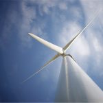 Aerogenerador de gran tamaño visto desde la base con palas girando a velocidad variable