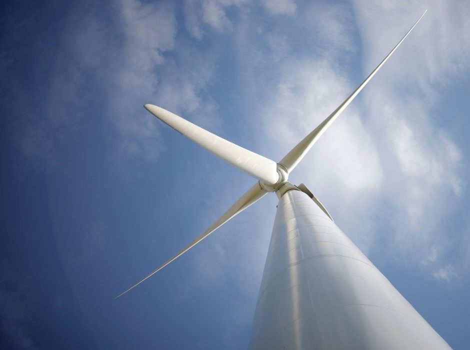 Aerogenerador de gran tamaño visto desde la base con palas girando a velocidad variable