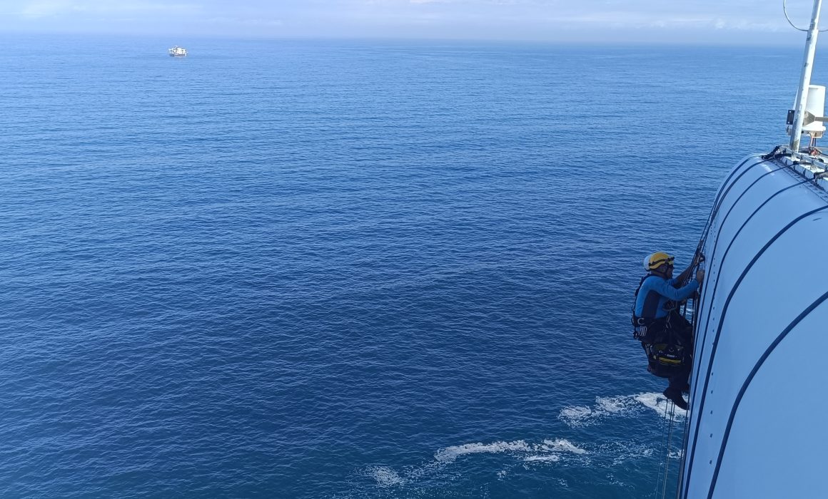 Técnico en trabajos verticales realizando mantenimiento en aerogenerador offshore sobre el mar