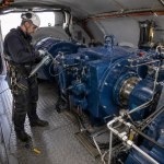 Técnico especializado realizando la lubricación de rodamientos en el interior de la nacelle de un aerogenerador durante una operación de mantenimiento eólico